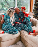 Family sitting on a couch in matching pajamas with a Christmas tree in the background.